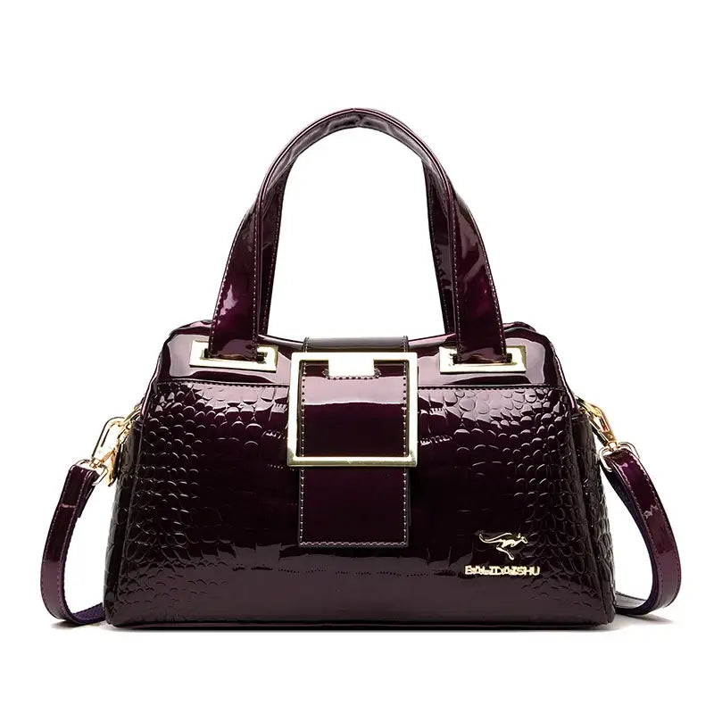 Luxury Designer Handbag in deep purple color with stylish handles and gold accents.